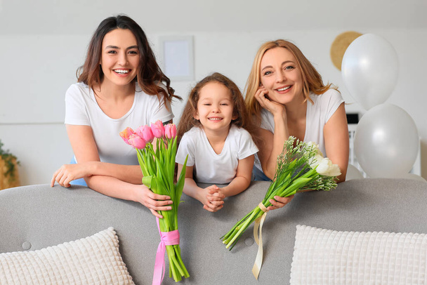Fiatal nő, kislánya és édesanyja virágokkal a nemzetközi nőnapon otthon - Fotó, kép