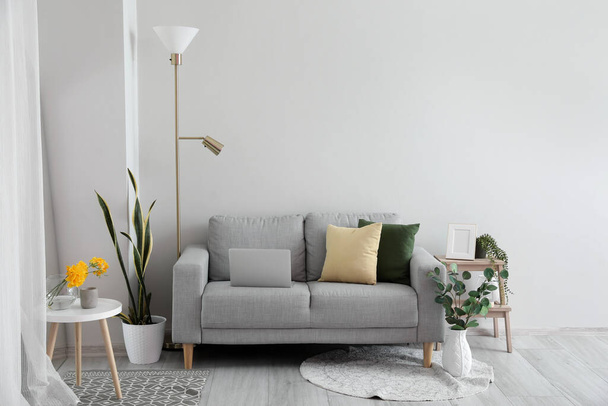 Interior of living room with sofa and floral decor near light wall - Foto, Bild