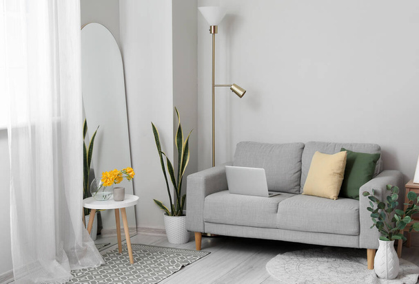 Elegante interno del soggiorno con divano e grande specchio vicino alla parete luminosa - Foto, immagini