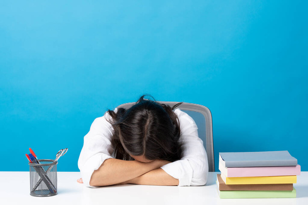 Jovem mulher dormindo cabeça na mesa isolada no fundo azul. Estresse, ansiedade e depressão no conceito de alunos. - Foto, Imagem