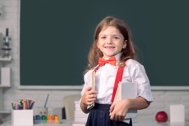 Portrait of cute, smiling girl in school uniform in classroom. Genius child, knowledge day. - Photo, Image