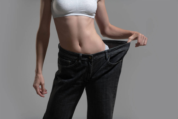 Thin woman in big pants, weight loss concepts. Slim girl with oversized big trousers. Woman weight loss. Woman with slim body after dieting. - Valokuva, kuva