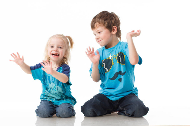 Portrait of a brother and sister, curly blond with blue eyes laughing merrily on a white background. Childrens emotions, happiness, joy, fun. Beautiful cute children. Friendship. - Fotó, kép