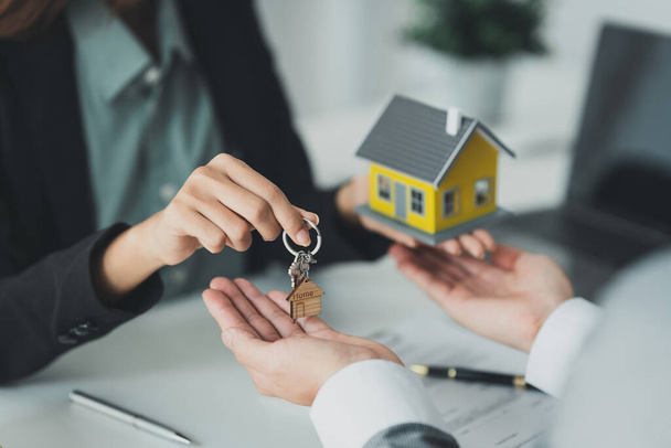 Close up Geschäftsfrau oder Immobilienmakler geben Hausschlüssel nach der Unterzeichnung des Vertrags für den Hauskauf. Bankmanager und Immobilienkonzept. - Foto, Bild