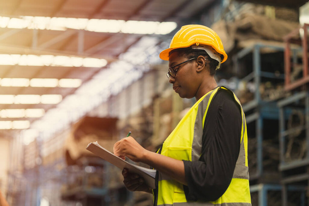 Engineer black women worker, Professional woman afican mechanical maintenance work in factory checking stock inventory in warehouse. - Photo, Image