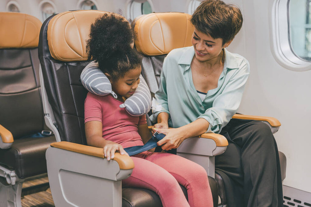 Niños en cabina de vuelo abrocharse el cinturón de seguridad viaje vacaciones con madre - Foto, Imagen