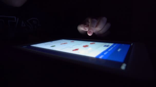 Verkkokaupoissa iPad. Tässä videossa on lähikuva nuoresta miehestä, joka käyttää digitaalista tablettia tehdäkseen ostoksia verkossa. Leike näyttää miehen kädet vierittämässä laitetta, kun hän tarkistaa. - Materiaali, video