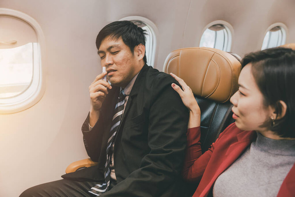 Asiático hombre de negocios movimiento masculino enfermo problema de salud durante volar a bordo en cabina de vuelo. - Foto, imagen