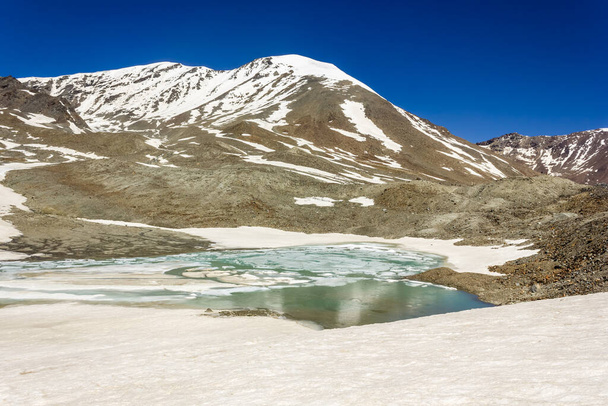 The partially frozen lake on top of the high altitude pass of Shingo La in the Great Himalayan range on the trek from Lahaul to Zanskar in North India. - Photo, image
