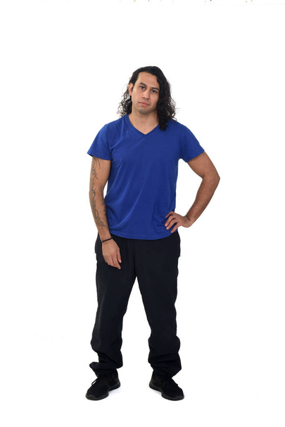 front view of a man with sportswear with tattoo on arms with hand on hip on white background - Foto, Imagen