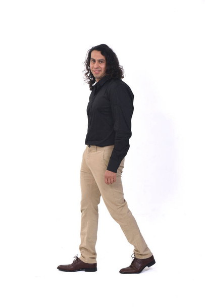 side view of a man with long hair walking and looking at camera  on white background - Foto, immagini