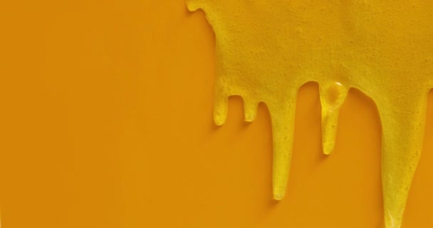 Cream liquid gel serum flows down on yellow texture, makeup and cosmetics background, skincare or hair product - Footage, Video