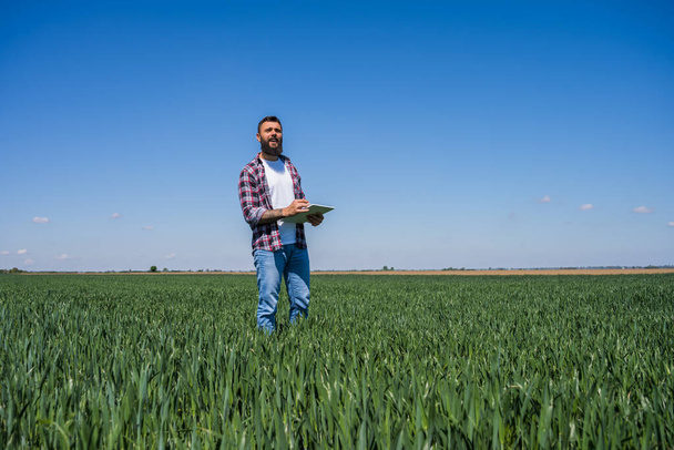 Farmer is examining the progress of crops in his barley field. - 写真・画像