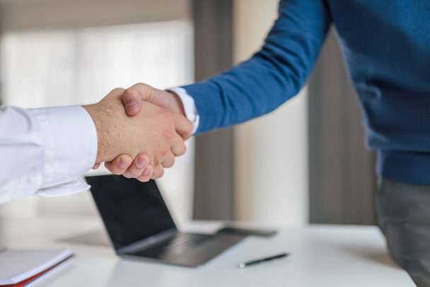 Male business partners shaking hands, Professionals congratulating in successful meeting, They are sitting at desk in corporate office. - Photo, Image