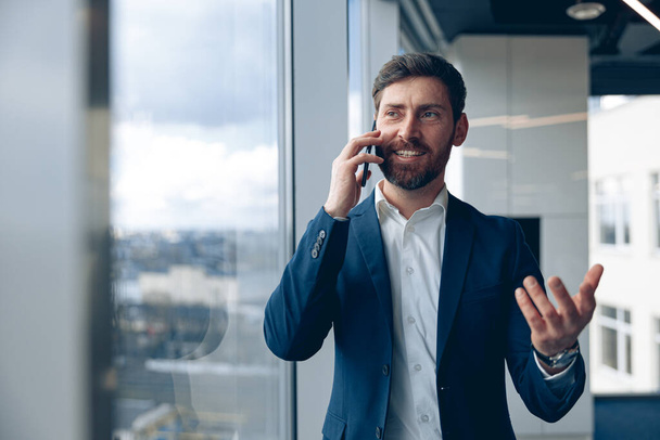 Retrato de homem inspirado usando telefone celular e fazendo uma chamada seu parceiro de negócios no escritório - Foto, Imagem