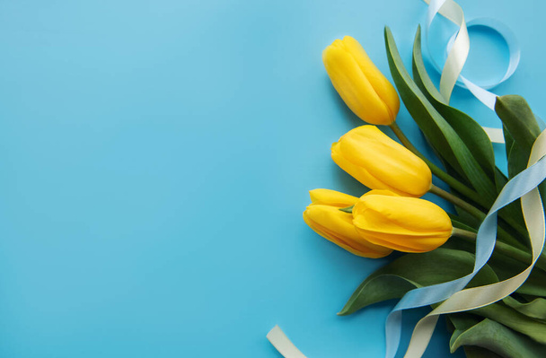Bouquet of beautiful yellow tulips on a blue background - Foto, imagen