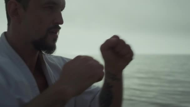 Close up focused fighter training hands punches on sunset beach. Active man exercising on soft evening sunlight outdoors. Karate sportsman practicing martial arts on nature. Physical strength concept. - Materiaali, video
