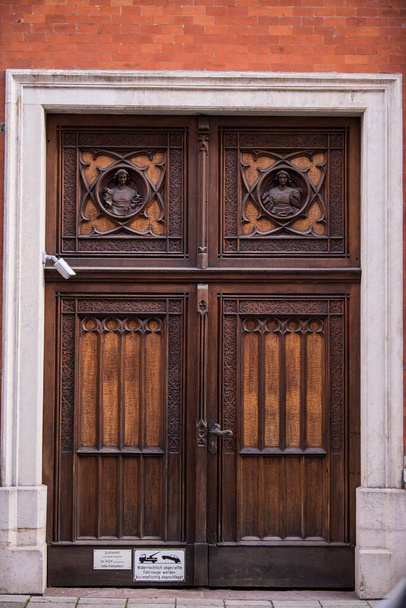 München, Duitsland - 01 mei 2022: Oude decoratieve hoofdingang houten deur. - Foto, afbeelding