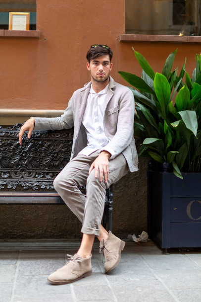 красивый итальянский темноволосый парень сидит элегантно одетый. Высокое качество фото - Фото, изображение