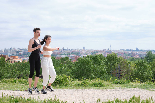 Young sporty couple running and checking the smartwatch outdoors. Two jogger friends. - Foto, immagini