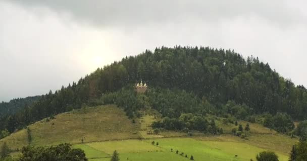Church on top of a hill in the middle of a green forest. Its snowing, orange sunset over the trees. High quality 4k footage - Metraje, vídeo