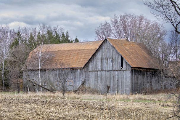 An old wooden barn sits idle on a country road in Ontario, Canada - Foto, imagen