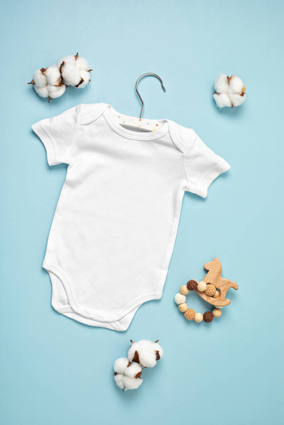 環境に優しい赤ちゃんのアクセサリーと有機綿で作られた白い幼児のボディスーツのモックアップ。ブランド、ロゴ、広告のためのワンセイテンプレート。フラットレイアウト、トップビュー - 写真・画像