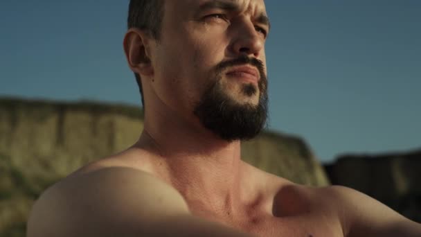 Closeup bearded karate man naked body warming up on seashore. Athletic sportsman exercising muscular hands on nature summer day. Brutal fighter stretching on sunlight standing beach. Sport lifestyle. - Materiaali, video