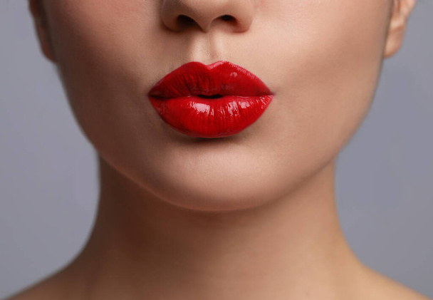 Closeup view of beautiful woman puckering lips for kiss	on grey background - 写真・画像