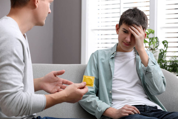 Father talking with his teenage son about contraception at home. Sex education concept - Foto, Imagem
