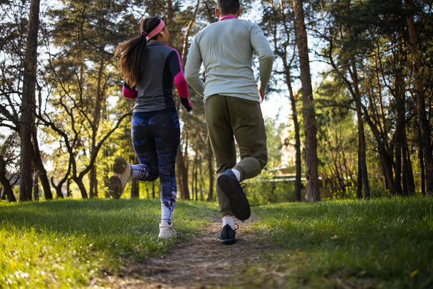 couple font du jogging dans le jardin du matin avec des arbres verts En été Avec une atmosphère chaude Avec de l'oxygène qui rend le système respiratoire sain Courir est une bonne partie de la réduction de l'excès de poids. - Photo, image