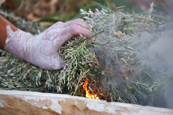 Australian Aboriginal Ceremony, man's hand with green branches and flame, start a fire for a ritual rite at a community even in Adelaide, South Australia - Foto, imagen