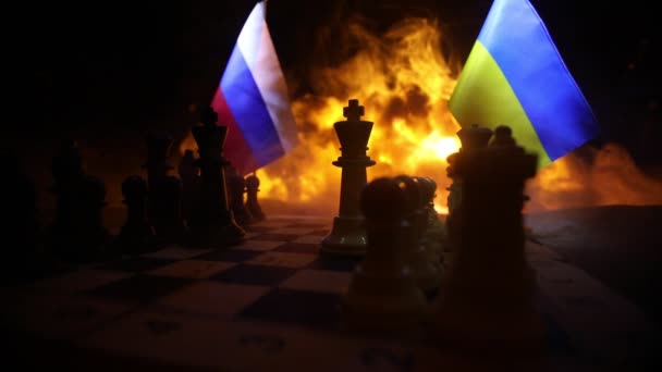 Savaş kavramı ya da küresel siyasetle manipülasyon. Rusya ve Ukrayna arasındaki savaş, patlamanın arka planında satranç tahtası ve ulusal bayraklar kullanan savaşın kavramsal görüntüsü. - Video, Çekim