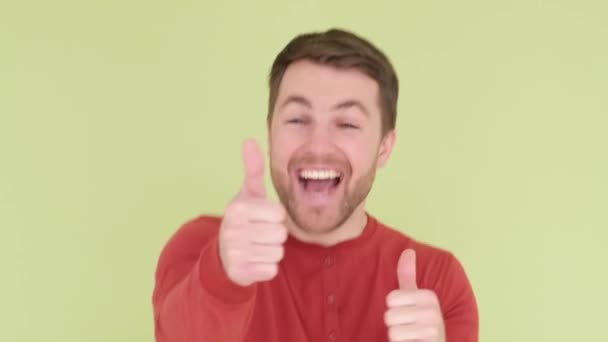 Happy man smiling, he shows thumbs up, wearing an orange sweater. Human hand gestures. - Felvétel, videó