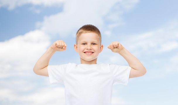 niño feliz en camiseta blanca flexionando bíceps
 - Foto, imagen
