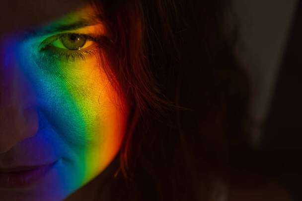 Close-up portrait of caucasian woman with ray of rainbow light on her face.  - Foto, Bild