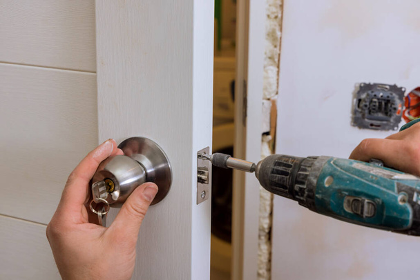 Builder in installing a door lock the door of a new house - Фото, изображение