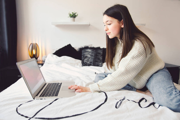 Nice teenage girl using a computer in her bedroom. - Photo, image