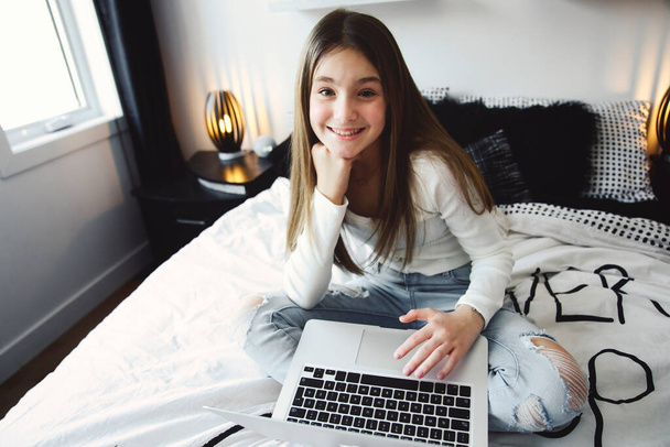 Nice teenage girl using a computer in her bedroom. - 写真・画像