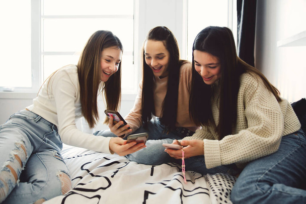 Group of teenage girls using a cellphone on the bedroom at home - Foto, Imagen