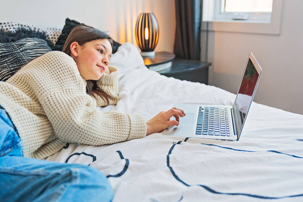 Nice teenage girl using a computer in her bedroom. - Foto, Bild