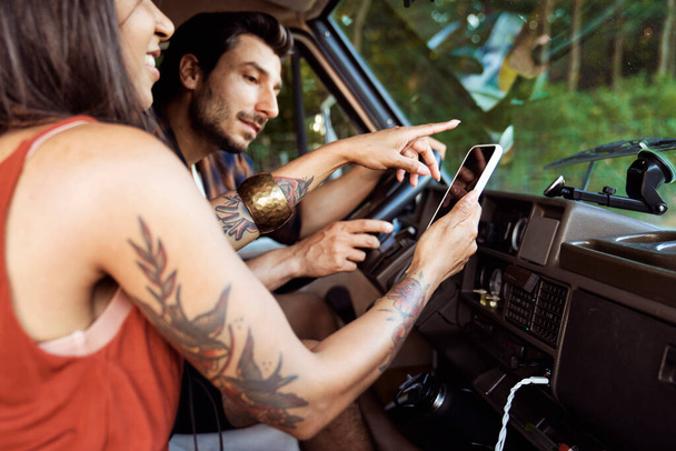 Молодая пара в машине ищет направление в мобильном телефоне - Фото, изображение