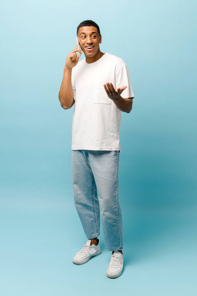 Vertical full length photo of African-American young guy talking on smartphone - Foto, Imagen