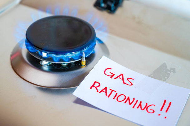 Gas stove, with blank note next to it with the text "gas rationing". Rationing and insufficiency in gas flows. Energy crisis. - Photo, Image