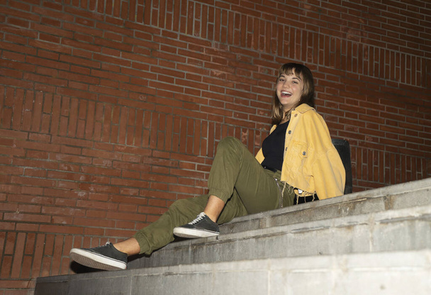 Blond woman sitting on staircase outdoors in the city at night - Foto, imagen