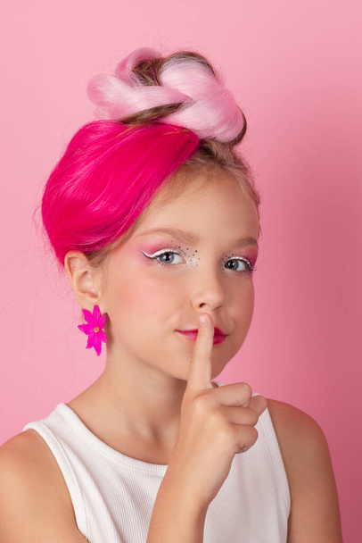 charming little girl with pink hairstyle and pink makeup. tween young model posing on pink background. - Valokuva, kuva