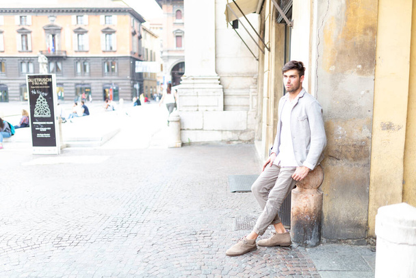handsome Italian dark-haired guy leaning against elegant palace. High quality photo - Zdjęcie, obraz