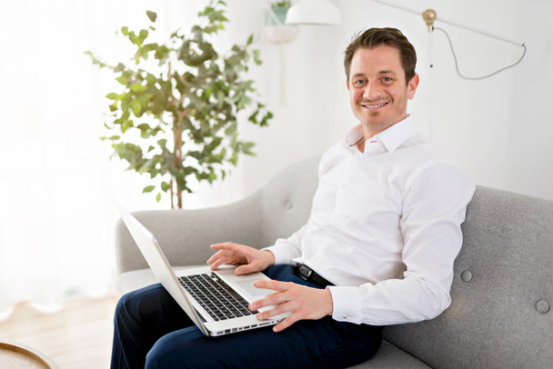 Щасливий усміхнений молодий чоловік дивиться і працює на комп'ютерний ноутбук вдома
 - Фото, зображення