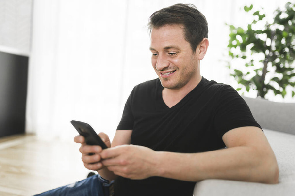 Hombre europeo usando su teléfono en la sala de estar - Foto, Imagen