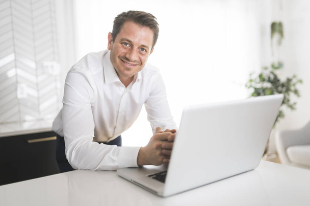 surprised business man working on laptop online sitting at kitchen table - Fotó, kép